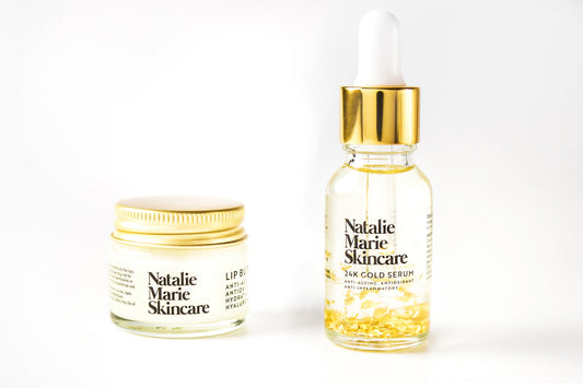 The Essential Duo: Natalie Marie Skincare 24K Gold Serum bottle and Hyaluronic Acid Lip Butter jar side by side with gold leaf